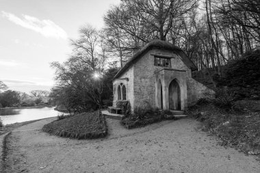 Wiltshire 'daki Stourhead Bahçeleri' ndeki Gotik Kulübe 'nin arkasında güneşin batışının siyah beyaz fotoğrafı.