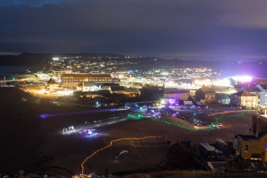 West Bay.Dorset.United Kingdom.April 19th 2023.Crowds of people are waiting for the torchlight procession at West Bay in Dorset clipart