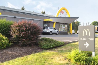 Utica, New York - 8 Temmuz 2025: 1940 yılında kurulan McDonald 's teşekkür işareti ve arabalı servis araçlarının geniş bulutlu görüntüsü, dünya çapında 39.000' den fazla yeri bulunan dünyanın en büyük fast-food zincirlerinden biridir.