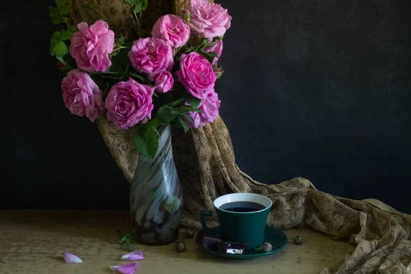 bouquet of pink roses and coffee cup on dark rustic wooden