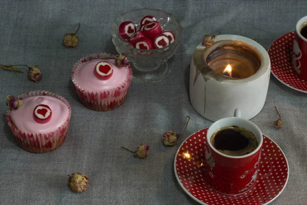 a cup of coffee, a cup of coffee and a red heart on the table with candle