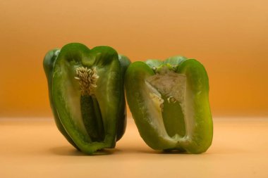 Sarı bir yüzeyde iki yeşil dolma biber.