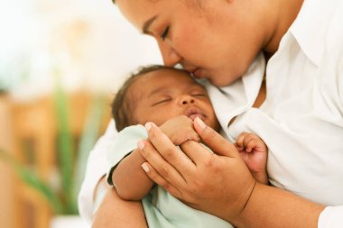 Afrikalı yeni doğmuş bir bebek, bir aylık, parmaklarını tutuyor, annesinin elini tutuyor, uykusuzca uyuyor, sıcak kucağında endişelenmeden uyuyor. Sığ bir alan derinliği olan resim, odak alanı elini seçin. konsept aile karışık ırk.