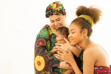 Geleneksel Afrika tarzı giyinen anne ve büyük kızı bir aylık bebek emziriyor. Mutlu bebek karışık ırk afro-Asya anneliğin sıcacık kollarında iyi uykular.. 