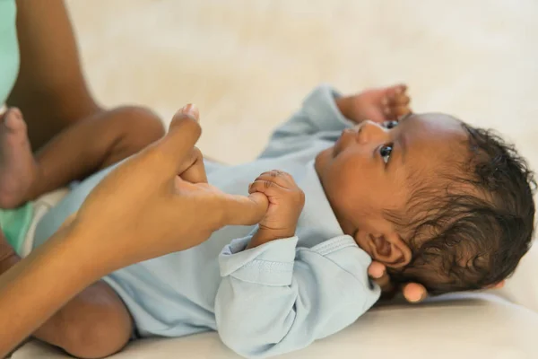 African Newborn baby one-month-old holding fingers mother\'s hand, Smile and look relax worry-free. image with a shallow depth of field, Select the focus area of the hand.