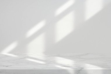 Pencereden Işık Işını ve Gölgesi ile Beyaz Stucco Duvarı Doku Arkaplanı olan Mermer Masa, Ürün Sunum Arkaplanı, Görünüm ve Moda İçin Uygun.
