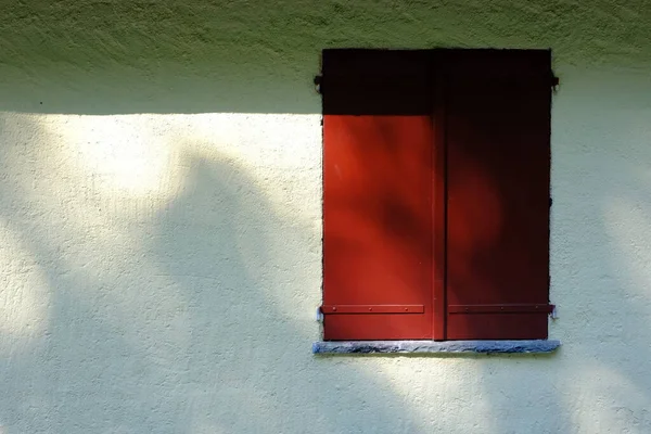 白い漆喰の壁に赤い木製の窓背景 — ストック写真