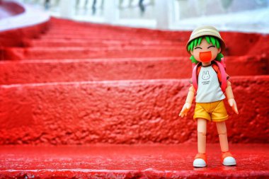 BANGKOK, THAILAND - 27 Kasım 2017: Minyatür Yotsuba Koiwai anime figürü Wat Saket Tapınağı 'ndaki Altın Dağ' a Kırmızı Beton Merdiven 'de duruyor. Yotsuba, Japon maga serisidir. ve Wat Saket Tapınağı Tayland 'ın simgesidir..