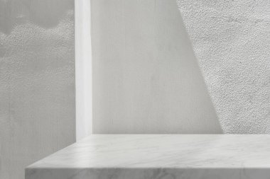 Beton duvar zemininde gölgesi ve ışık demeti olan en düşük beyaz mermer masa köşesi ürün sunumu, görüntü ve taklit için uygundur..