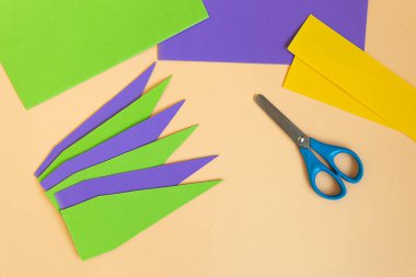 Mardi gras carnival jester hat on head made of paper . Step by step photo instructions DIY from 9 steps on neutral background. Step 5 of 9.