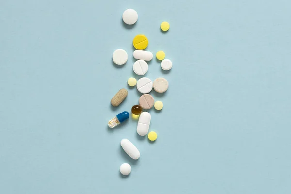 stock image A lot of colorful medicine pills on pastel blue background.