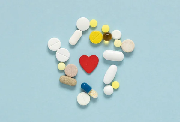 Different pills cardioglogy near red heart. Concept of heart diseases, problems with heart