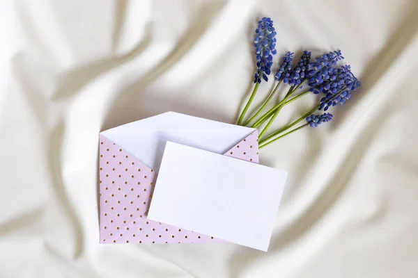 stock image Pink envelope with blank card and muscari flower on white background. Top view