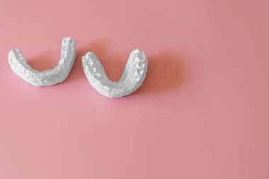 Hizalayıcılar için alçı kalıpları, dişler için alçı taşı. Pembe arka planda diş kalıbı. Görünmez diş telleri için diş kalıbı, hizalama ya da bruksizm için gece bekçisi. İnsan çenesi. 