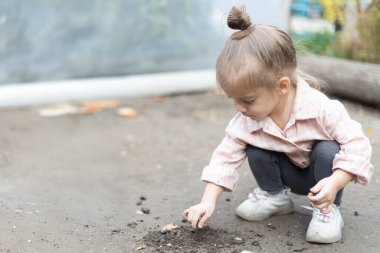 Genç bir çocuk yerde oturuyor, toprakla oynuyor ve onun dokusunu keşfediyor. Basit ve özgün bir çocukluk merakı ve doğayla bağlantı anı.