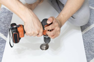 Montaj sırasında bir mobilya parçasını tutturmak için erkek ellerini tornavida ile kapat. Görüntü, DIY ev geliştirmesindeki kesinlik ve işçiliği vurguluyor
