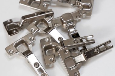 Bir gardırop dolabının metal menteşeleri yakın planda gösteriliyor. Mobilya montajı, DIY montajı ve ev yenileme temaları için uygun
