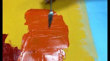 Bir ressamın palet bıçağını kullanarak tuvale canlı turuncu boya sürdüğü yakın çekim videosu. Yaratıcılık, sanat, soyut ifade ve sanatsal süreç temaları için uygundur
