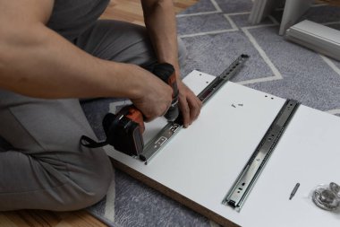 Evde gardırop monte etmek için tornavida kullanan bir adam. El ve aletleri yakın plan. DIY ve ev yenileme kavramı