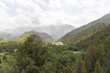 Yazın sisli Sayram Ugam dağlarının geniş açılı görüntüsü. Yumuşak ışık ve uzak tepelerin huzurlu atmosferi