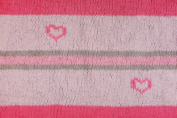 pink heart of the warm woolen threads on knitted fabric