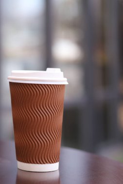 Masasında kahve olan bir fincan, bulanık bir arka plan. Dikey Yönlendirme