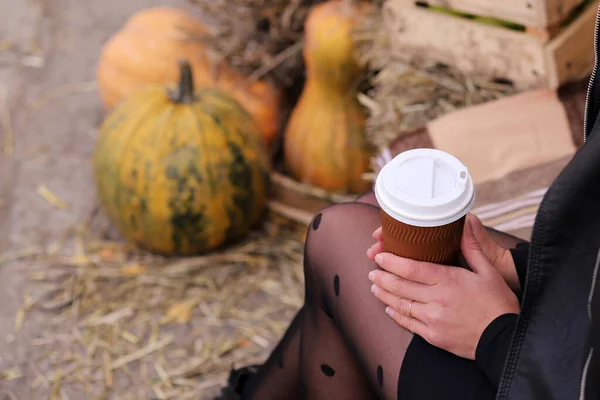 Girl holding a glass of coffee on an autumn background