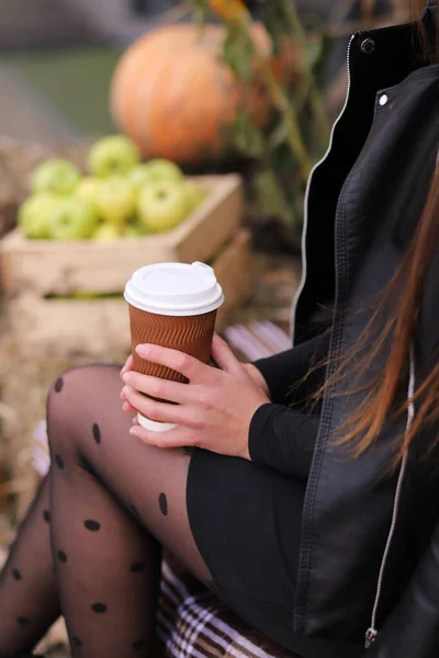 Girl holding a glass of coffee on an autumn background. Vertical Orientation