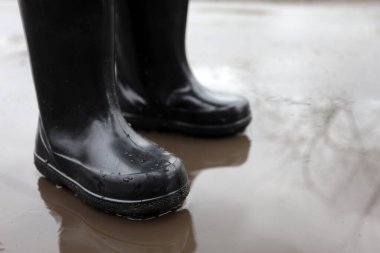 Yağmurdan sonra su birikintisinde lastik çizmeli bir çocuk