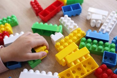 Çocuk masanın üstünde bir tasarımcıyla oynuyor, bloklardan duvarlar inşa ediyor.