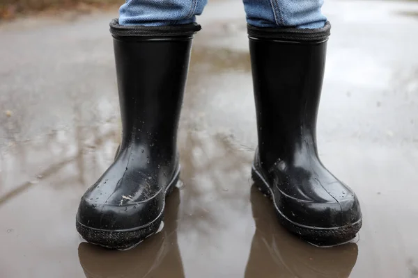 child in rubber boots in a puddle after rain