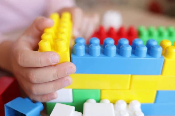 Stock image child builds a house from a constructor of colored bricks, hands close-up