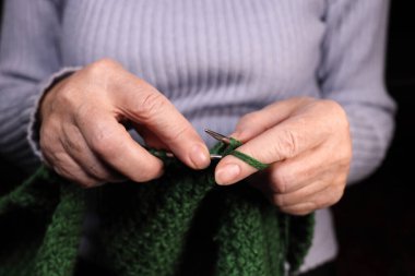 Kadın iplikten örgü iğneleriyle örüyor. Ev yapımı kıyafetler, boş zaman, hobi.