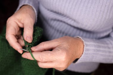 Kadın iplikten örgü iğneleriyle örüyor. Evde örgü örme kavramı