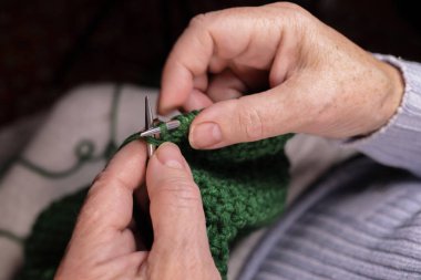 Kadın iplikten örgü iğneleriyle örüyor. Ev yapımı kıyafetler, boş zaman, hobi.