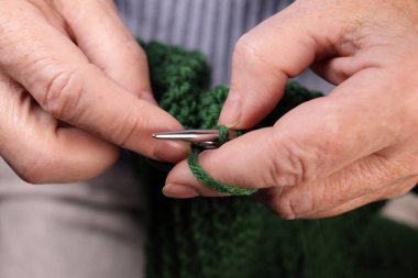 Kadın elleri yeşil ipliklerle örgü örer. El yapımı örgü.