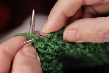 Kadın elleri yeşil ipliklerle örgü örer. El yapımı örgü.