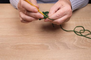 Kadın masanın üzerinde yün bir kazak örüyor. Ev yapımı kıyafetler, boş zaman, hobi.