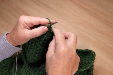 Kadın iplikten örgü iğneleriyle örüyor. Evde örgü örme kavramı