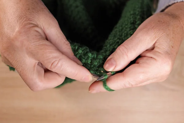 stock image Woman hands knits with green threads close up. Handmade hobby knitting