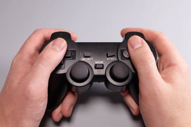 Male hands hold a joystick, gamepad, playing video games on a gray background