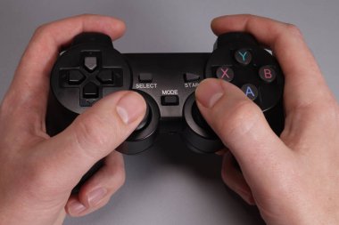 Male hands hold a joystick, gamepad, playing video games on a gray background