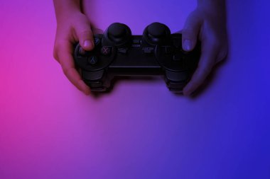 Children's hands hold a joystick, gamepad, playing video games in ultraviolet light