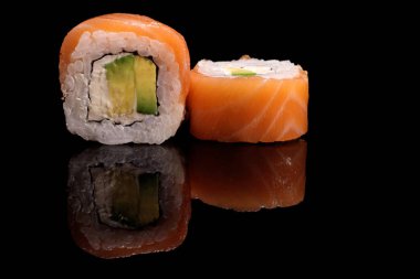 Sushi, rolls with salmon and avocado close-up on a mirror black surface