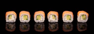 Row of sushi, rolls with salmon and avocado on a mirror black surface. Horizontal banner