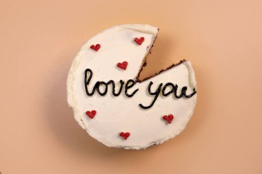 Trendy bento cake delicate biscuit with the inscription love you with a cut off piece on a light background