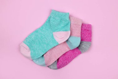 Stack of baby socks on pink background