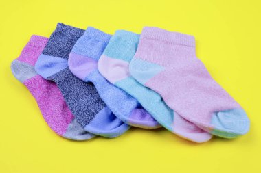 stack of colored children's socks on a yellow background