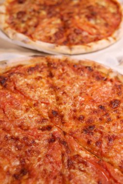 Whole pizzas with cheese, ham and tomatoes in a delivery box. Vertical Orientation