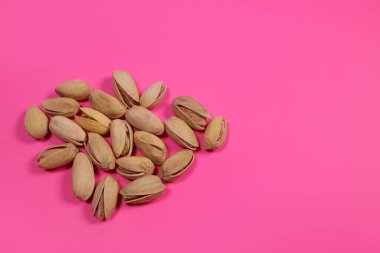 Organic pistachios nuts in shell on pink background